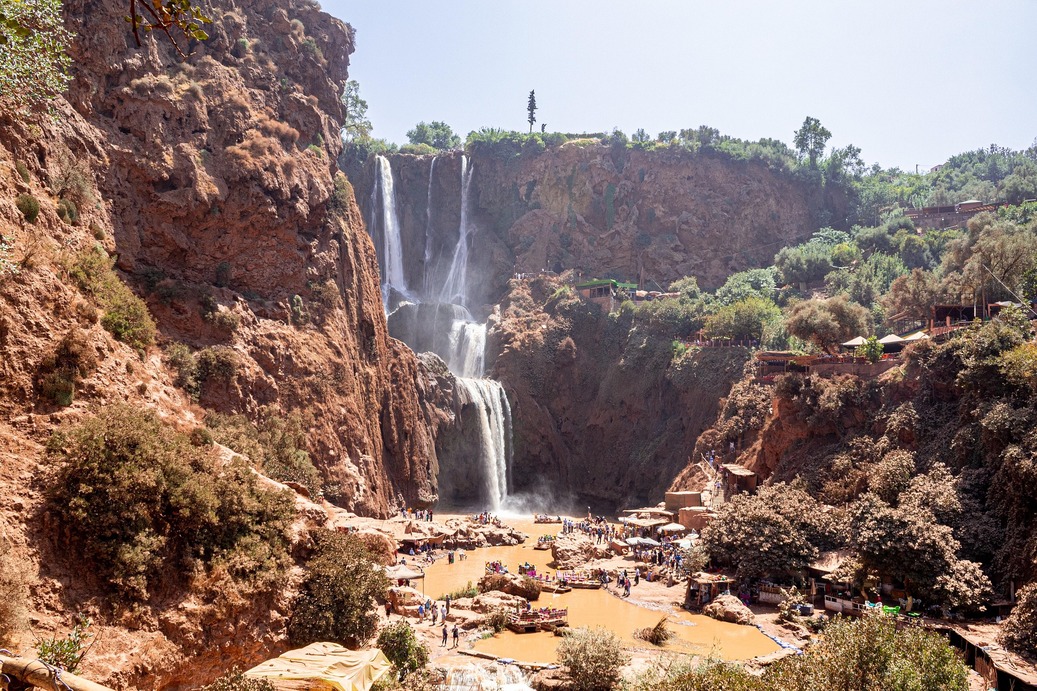 Ouzoud Waterfalls surrounded by red cliffs and green olive trees in Morocco